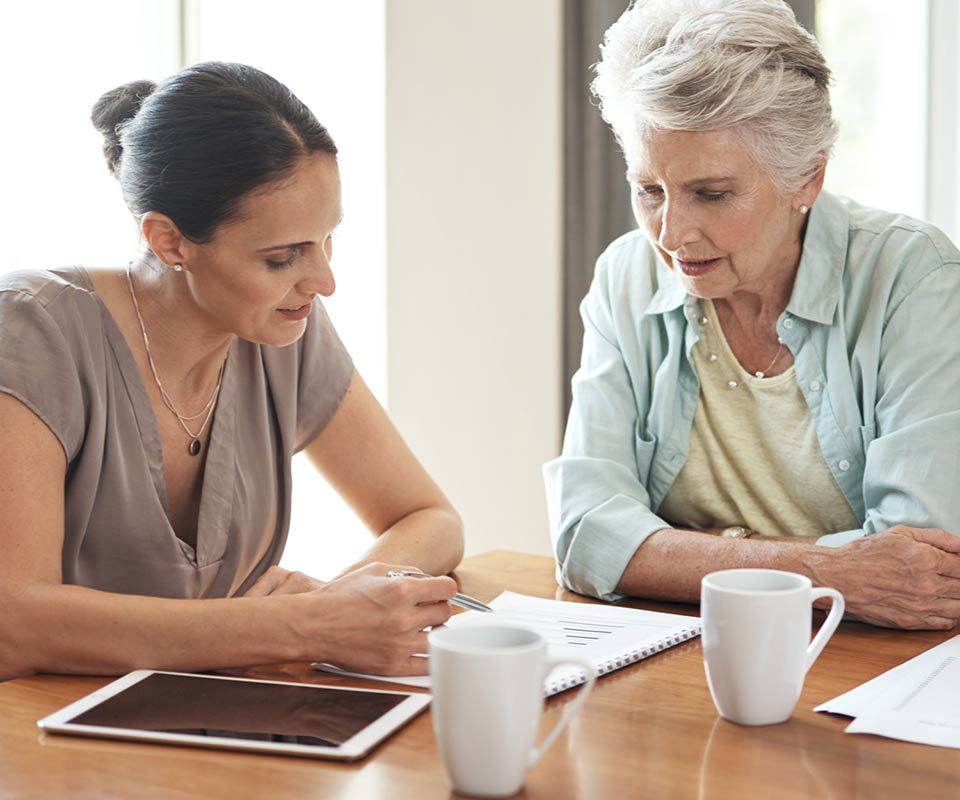 Older and younger women at table together reviewing a document