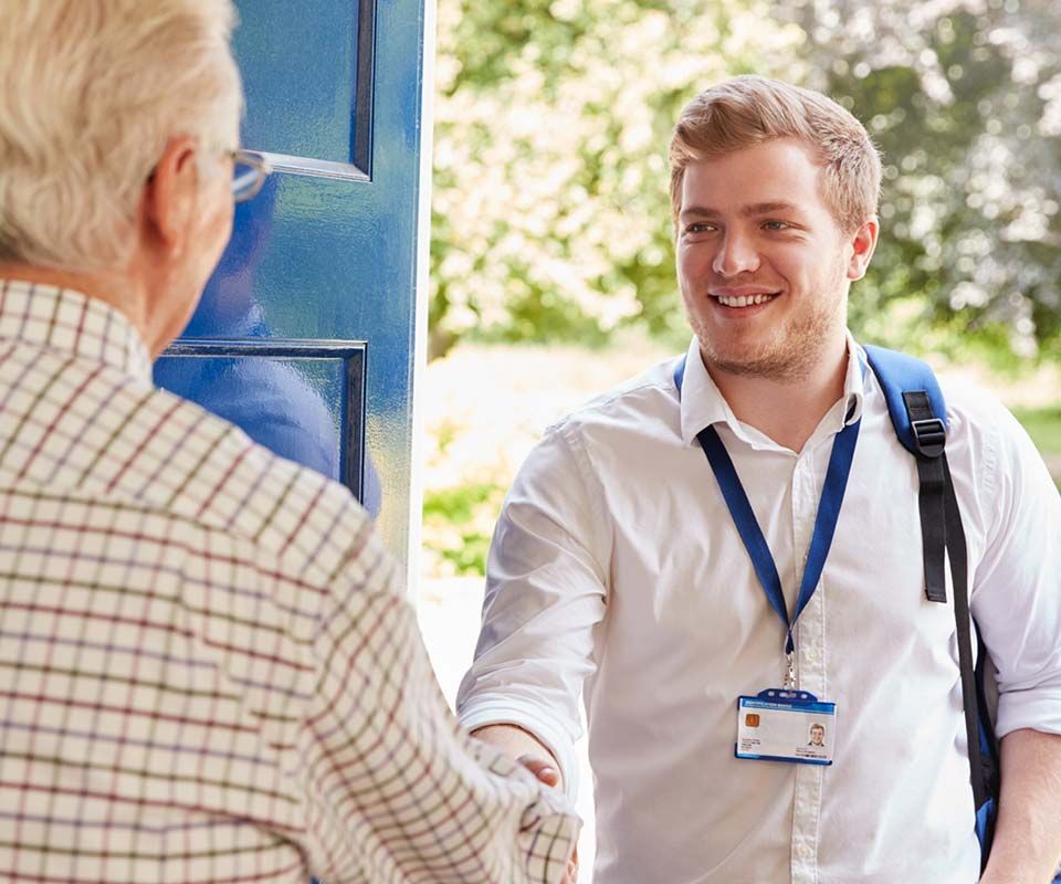 Young man at door shaking hand with older man in house